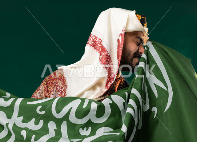 كروما لرجل عربي سعودي خليجي، يحمل علم السعوديه, يرتدي الزي الشعبي التقليدي العريق, دقلة أهل المنطقه الوسطى, الإحتفال باليوم الوطني السعودي، هوية اليوم الوطني السعودي 92، أزياء سعودية تراثية، يوم التأسيس السعودي، العيد الوطني السعودي, خلفيه خضراء