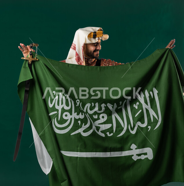 كروما لرجل عربي سعودي خليجي، يرتدي الزي الشعبي التقليدي العريق, دقلة أهل المنطقه الوسطى, يحمل السيف مع علم السعوديه, الإحتفال باليوم الوطني السعودي، هوية اليوم الوطني السعودي 92، أزياء سعودية تراثية، يوم التأسيس السعودي، العيد الوطني السعودي, خلفيه خضراء