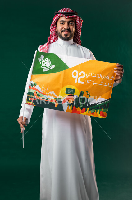 كروما لرجل عربي سعودي خليجي يرتدي الثوب السعودي التقليدي، يحمل علم اليوم الوطني السعودي، الإحتفال باليوم الوطني السعودي 92، هوية اليوم الوطني السعودي، خلفية خضراء، يوم التأسيس السعودي، العيد الوطني السعودي, خلفيه خضراء