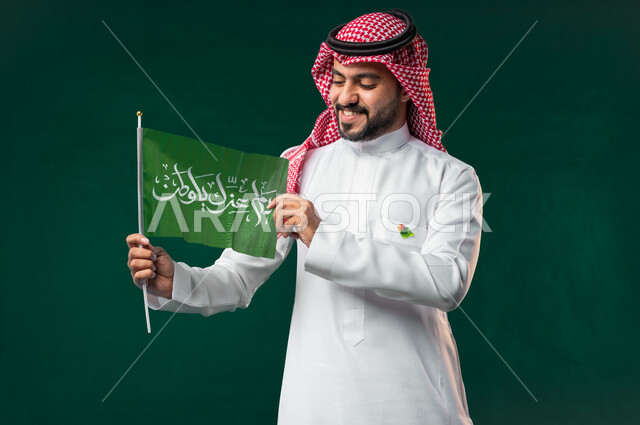 كروما لرجل عربي سعودي خليجي يرتدي الثوب السعودي التقليدي، يحمل علم اليوم الوطني السعودي، الإحتفال باليوم الوطني السعودي 92، هوية اليوم الوطني السعودي، خلفية خضراء، يوم التأسيس السعودي، العيد الوطني السعودي, خلفيه خضراء