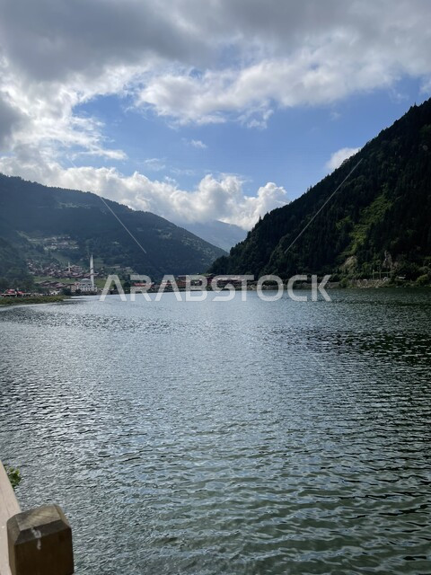 اطلالة جميلة على واجهة بحرية مع خلفية الجبال، الاشجار والنباتات الخضراء، السماء الملبدة بالغيوم، جمال الطبيعة الخلابة، خلفية الطبيعة