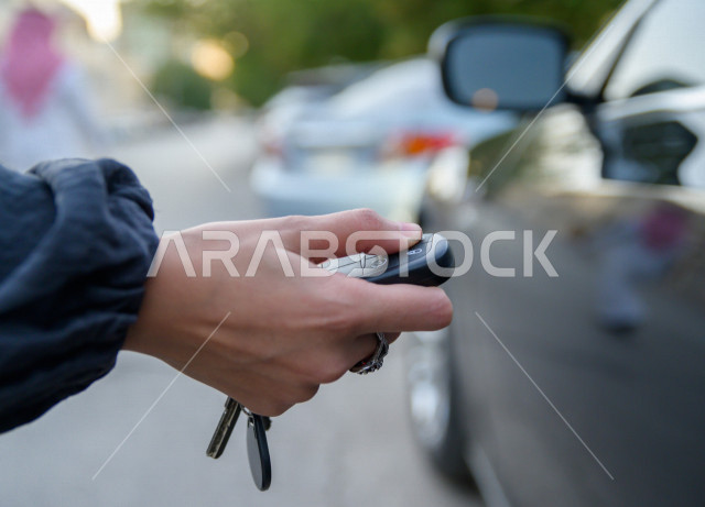 صورة مقربة ليد مرأه عربية سعودية خليجية تضغط على زر مفتاح السيارة عن بعد ، القيادة في المملكة العربية السعودية