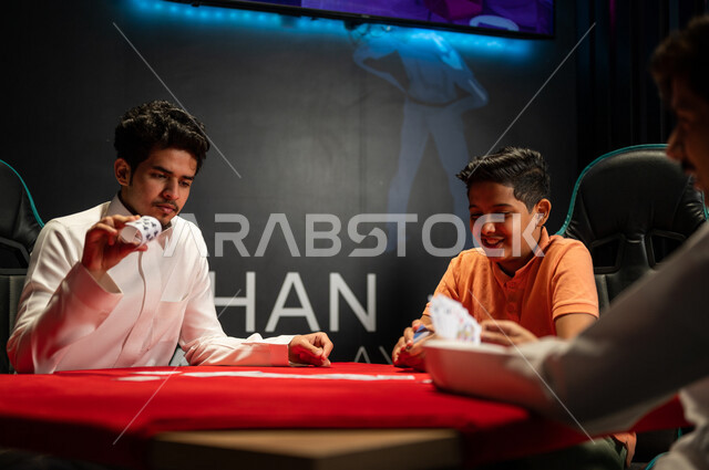 صورة مقربة لمجموعة من الشباب العرب المراهقين خليجيين سعوديين يلعبون لعبة الورق في المقهى بالسعودية، أصدقاء يتحدون بعضهم في لعبة الشدّة، لاعبين عرب سعوديين، هاند السعودي، قضاء أوقات ممتعة مع الأصدقاء، أنشطة ترفيهية، ألعاب الورق الممتعة