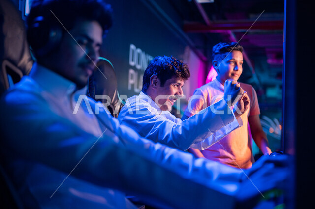 Arab youth Gulf Saudi teenagers in the electronic games store, wearing a headset and playing electronic video games, gestures indicating winning and happiness in the challenge, recreational activities, computer entertainment games, spending leisure time p