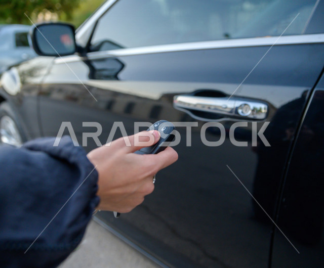 صورة مقربة ليد مرأه عربية سعودية خليجية تضغط على زر مفتاح السيارة عن بعد ، القيادة في المملكة العربية السعودية