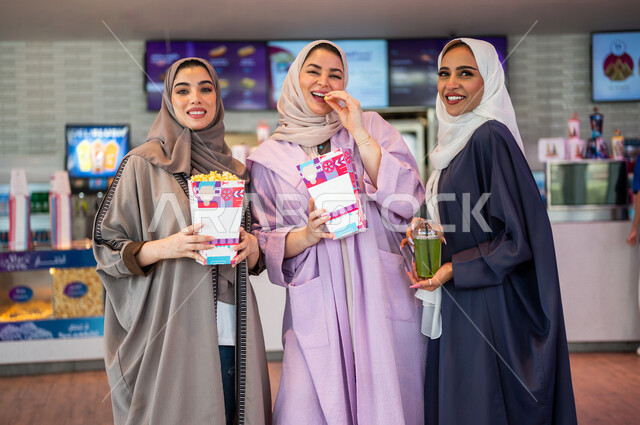 صديقات عربيات سعوديات خليجيات في ردهة الإستقبال داخل السينما, النظر الى الكاميرا، شراء المشروبات والفشار, الإستعداد للدخول الى صالة العرض، قضاء أوقات ممتعة مع الأصدقاء، مشاهدة الأفلام والعروض المسرحية، عطلة نهاية الأسبوع، سينما ومسرح، أنشطه ترفيهيه