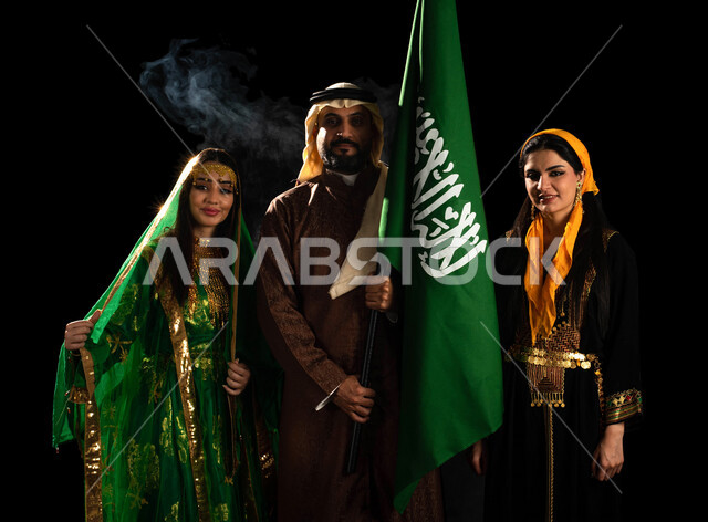بورتريه لمجموعة من الرجال والنساء العرب السعوديون الخليجيون يرتدون الزي السعودي الشعبي التقليدي, أزياء المناسبات والإحتفالات الوطنية في المنطقه الوسطى والمنطقه الشماليه، رفع علم السعوديه, ذكرى اليوم الوطني السعودي 92, أزياء يوم التأسيس, خلفيه سوداء