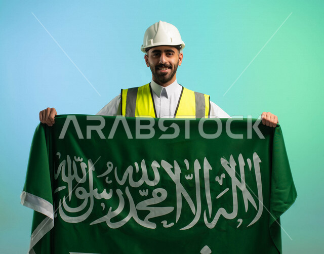مهندس عربي خليجي سعودي يعمل في مجال الهندسة، يرتدي الخوذة وسترة الحماية، يحمل علم المملكة العربية السعودية، يحتفل باليوم الوطني السعودي، مهن ووظائف السعودية، العمالة السعودية، فرص عمل، مهنة الهندسة، اليوم الوطني السعودي، خلفية كروما