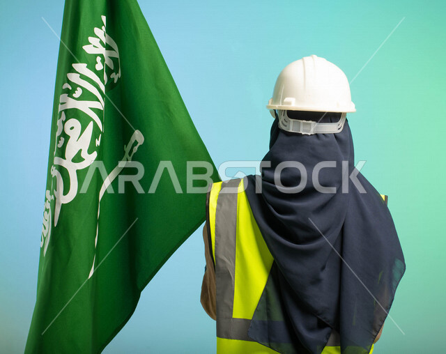 زاوية من الخلف، مهندسة عربية خليجية سعودية تعمل في مجال الهندسة، ترتدي الخوذة وسترة الحماية، تحمل علم السعودية، تحتفل باليوم الوطني السعودي، مهن ووظائف السعودية، العمالة السعودية، فرص عمل، مهنة الهندسة، اليوم الوطني السعودي، خلفية كروما