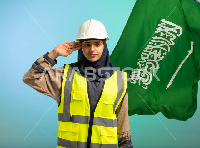 مهندسة عربية خليجية سعودية تعمل في مجال الهندسة، ترتدي الخوذة وسترة الحماية، تلقي تحية السلام لوطنها الحبيب، خلفية علم المملكة العربية السعودية، مهن ووظائف السعودية، العمالة السعودية، فرص عمل، مهنة الهندسة، اليوم الوطني السعودي، خلفية كروما
