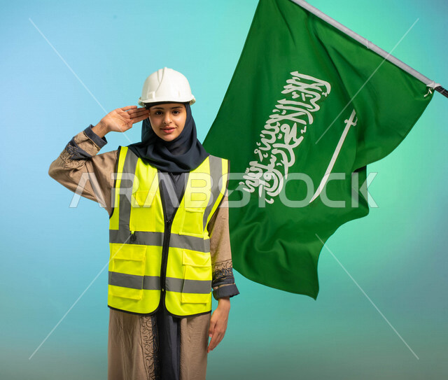 مهندسة عربية خليجية سعودية تعمل في مجال الهندسة، ترتدي الخوذة وسترة الحماية، تلقي تحية السلام لوطنها الحبيب، خلفية علم المملكة العربية السعودية، مهن ووظائف السعودية، العمالة السعودية، فرص عمل، مهنة الهندسة، اليوم الوطني السعودي، خلفية كروما