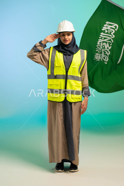 مهندسة عربية خليجية سعودية تعمل في مجال الهندسة، ترتدي الخوذة وسترة الحماية، تلقي تحية السلام لوطنها الحبيب، خلفية علم السعودية، مهن ووظائف السعودية، العمالة السعودية، فرص عمل، مهنة الهندسة، اليوم الوطني السعودي، خلفية كروما، صورة بالطول الكامل