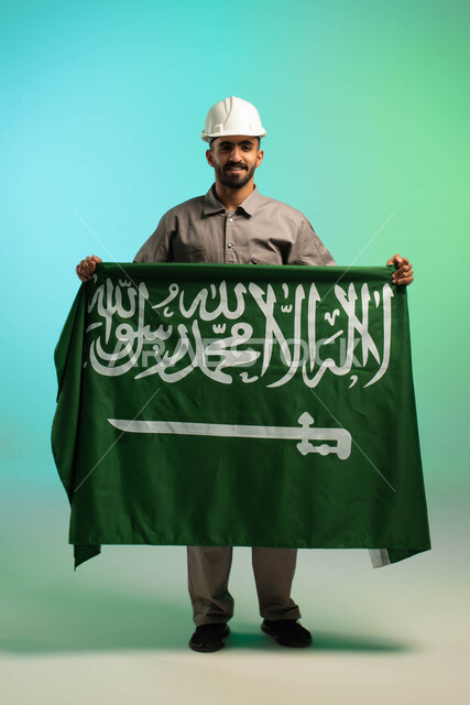 Saudi Arabian Gulf technical engineer working in the construction sector, wearing a protection helmet, holding the Saudi flag, Saudi professions and jobs, Saudi labor, job opportunities, electrical technician profession, business and maintenance, Saudi Na