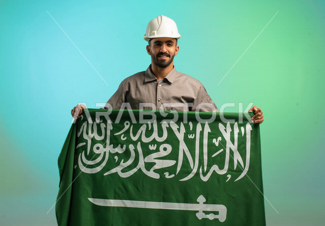 مهندس فني عربي خليجي سعودي يعمل في قطاع الإنشاءات، يرتدي خوذة الحماية، يحمل علم السعودية، يحتفل باليوم الوطني، مهن ووظائف سعودية، العمالة السعودية، فرص عمل، مهنة فني كهرباء، الأعمال والصيانة، اليوم الوطني السعودي، خلفية كروما