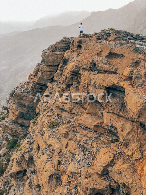 صورة إبداعية لجبل هاط في ولاية الحمراء بسلطنة عمان ، جبال سلطنة عمان ، رجل سائح يقف على جبل هاط بعمان ، أماكن سياحية بسلطنة عمان ، المرتفعات الجبلية ، أجواء ضبابية