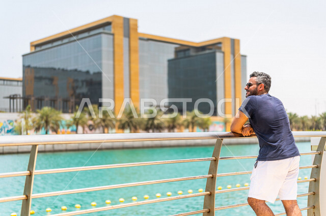 رجل عربي خليجي سعودي، يرتدي النظارة الشمسية، يقضي وقت ممتع على كورنيش جدة، كورنيش جدة السياحي، واجهة جدة البحرية، أماكن سياحية ترفيهية بالمملكة العربية السعودية، الإستجمام والتنزه في الهواء الطلق، خلفية ضبابية، أنشطة ترفيهية في جدة