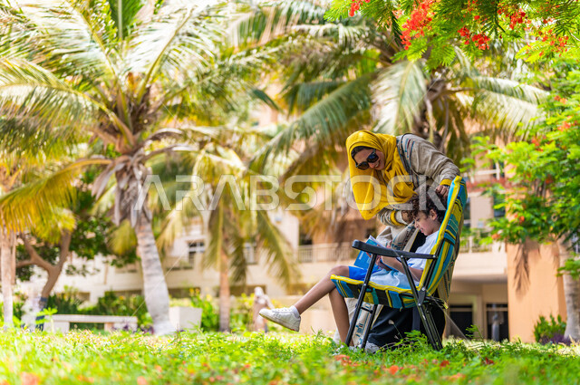 مرأة عربية خليجية سعودية تقضي وقت ممتع برفقة إبنها في إحدى الحدائق السياحية الترفيهية في المملكة العربية السعودية، تعابير تدل على السعادة، قضاء أوقات عائلية ممتعة، مفهوم الأسرة السعيدة، جلسات هادئة، خلفية الطبيعة، حدائق عامة