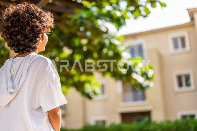 صورة مقربة لولد عربي خليجي سعودي، يتجول في الأحياء السكنية الراقية بالسعودية، كمباوند سكني بالمملكة العربية السعودية، مجمع سكني راقي بالسعودية، تصميم هندسي معماري حديث، فلل سكنية، الإسكان العائلي بالسعودية، جودة الحياة