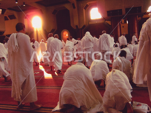 A group of Muslim pilgrims wearing the Ihram dress, performing prayer at the Sayeda Aisha Mosque in the Miqat al-Tana’im in Makkah, preparing to perform Hajj in Makkah al-Mukarramah, Saudi Arabia, Hajj season 2022, worshiping and getting closer to God