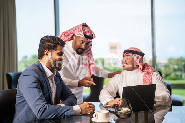 فريق عمل عربي سعودي خليجي مع رجل عربي يرتدي البدلة الرسمية, الجلوس في المقهى، إستخدام جهاز الحاسوب المحمول، مناقشة مهام العمل، شركة سعودية، بيئة عمل سعودي، زملاء عمل، الشراكة والتعاون، إجتماع عمل, متابعة الأعمال, تحقيق استراتيجيات العمل