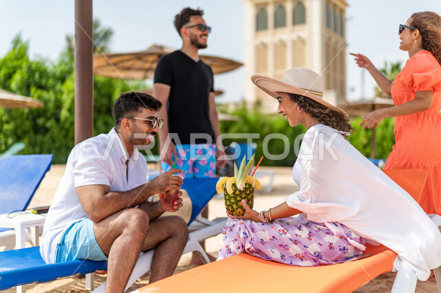 مجموعة من الأصدقاء العرب الخليجيين السعوديين يتقابلون على شاطيء بحر جدة، الاستمتاع بالمشروبات الصيفية  المنعشة على شاطئ البحر، دردشة ومحادثات، المتعة والاستجمام على  بحر جدة السياحي، أزياء صيفية