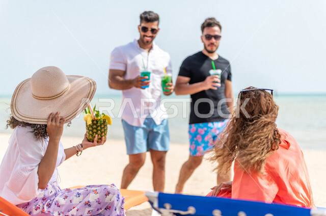 مجموعة من الأصدقاء العرب الخليجيين السعوديين يتقابلون على شاطيء بحر جدة، الاستمتاع بالمشروبات الصيفية  المنعشة على شاطئ البحر، دردشة ومحادثات، المتعة والاستجمام على  بحر جدة السياحي، أزياء صيفية