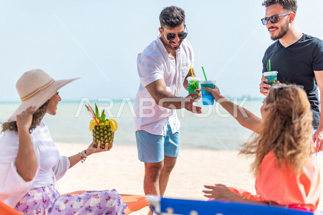 مجموعة من الأصدقاء العرب الخليجيين السعوديين يتقابلون على شاطيء بحر جدة، الاستمتاع بالمشروبات الصيفية  المنعشة على شاطئ البحر، دردشة ومحادثات، المتعة والاستجمام على  بحر جدة السياحي، أزياء صيفية