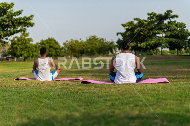 صورة من الخلف لشابان عربيان خليجيان سعوديان يمارسان رياضة اليوغا التأملية، ممارسة نشاط رياضي، أنشطة و تمارين رياضية، التأمل و الاسترخاء، الرياضة والنشاط البدني، تمارين اللياقة البدنية، أسلوب حياة صحي، لياقة ورشاقة