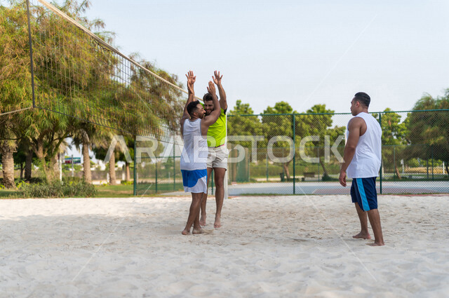 A team of Saudi Arabian Gulf friends playing volleyball, celebration of scoring goals and victory, beach volleyball, recreational sports activities, beach volleyball in summer, youth activities and sports, competitions and challenges, physical activity
