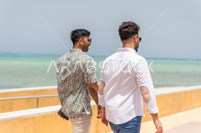 صديقان عربيان سعوديان خليجيان يمارسان رياضة المشي في ممشى كورنيش جده, شاطيء سياحي, نشاط بدني في الهواء الطلق, التنزه في جده, دردشة ومحادثات, الإستمتاع مع الأصدقاء, الواجهه البحريه لمدينة جده