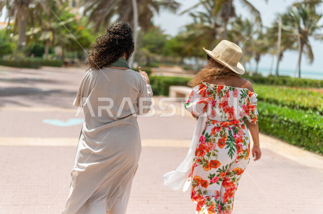 صديقتان عربيتان سعوديتان خليجيتان تمارسان رياضة المشي في ممشى كورنيش جده, شاطيء سياحي, نشاط بدني في الهواء الطلق, التنزه في جده, دردشة ومحادثات, الإستمتاع مع الأصدقاء, الواجهه البحريه لمدينة جده, عطله صيفيه