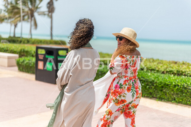 صديقتان عربيتان سعوديتان خليجيتان تمارسان رياضة المشي في ممشى كورنيش جده, شاطيء سياحي, نشاط بدني في الهواء الطلق, التنزه في جده, دردشة ومحادثات, الإستمتاع مع الأصدقاء, الواجهه البحريه لمدينة جده, عطله صيفيه