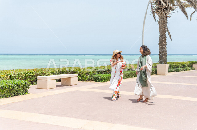 صديقتان عربيتان سعوديتان خليجيتان تمارسان رياضة المشي في ممشى كورنيش جده, شاطيء سياحي, نشاط بدني في الهواء الطلق, التنزه في جده, دردشة ومحادثات, الإستمتاع مع الأصدقاء, الواجهه البحريه لمدينة جده, عطله صيفيه