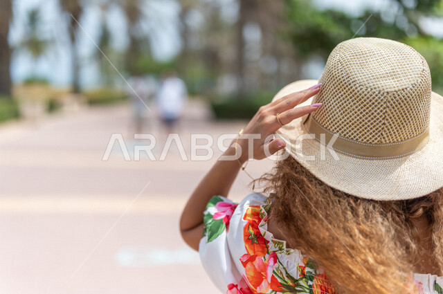 تصوير من الخلف لإمرأه عربيه سعوديه خليجيه تمارس رياضة المشي في ممشى كورنيش جده, شاطيء سياحي, نشاط بدني في الهواء الطلق, التنزه في جده, الواجهه البحريه لمدينة جده, عطله صيفية