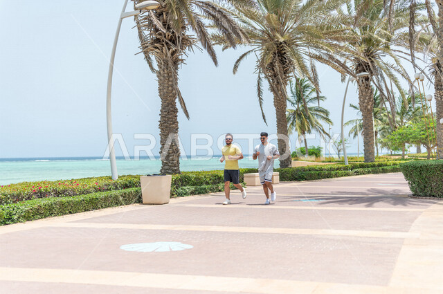 صديقان عربيان سعوديان خليجيان يمارسان رياضة الجري, الصحه واللياقه الجسديه, ممارسة رياضة المشي في ممشى كورنيش جده, شاطيء سياحي, نشاط بدني في الهواء الطلق, التنزه في جده, رياضة الصباح, الواجهه البحريه لمدينة جده