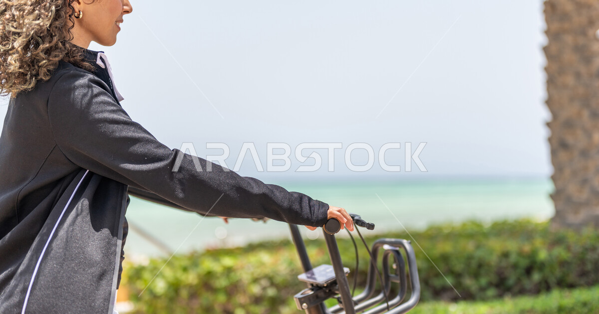 A Saudi Arabian Gulf man and woman riding an electric scooter in Jeddah