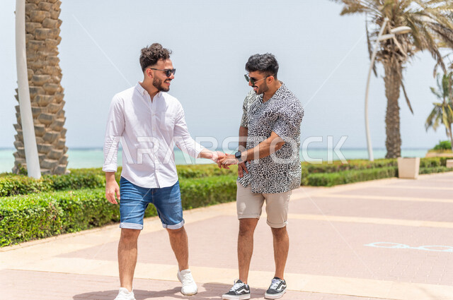 صديقان عربيان سعوديان خليجيان يمارسان رياضة المشي في ممشى كورنيش جده, شاطيء سياحي, نشاط بدني في الهواء الطلق, التنزه في جده, دردشة ومحادثات, الإستمتاع مع الأصدقاء, الواجهه البحريه لمدينة جده