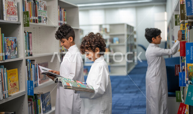 طلاب عرب سعوديون خليجيون يقومون بقراءة الكتب داخل المكتبة المدرسية، الاستمتاع بقراءة الكتب، مفهوم التعليم الذاتي, مكتبة المدرسة، بيئه مدرسيه تعليميه متطوره, المدارس المبتكره, جودة التعليم, مدارس أكاديميه في المملكة العربية السعودية