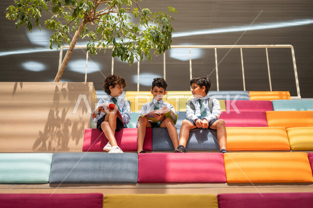 مجموعه من الطلاب العرب السعوديون الخليجيون يجلسون على الأدراج في بهو المدرسه, المذاكره والمراجعه, الإستعداد للإمتحانات, بيئه مدرسيه تعليميه متطوره, التعليم الذكي, عالم جديد من التعليم، المدارس المبتكره, جودة التعليم, مدارس أكاديميه في السعوديه