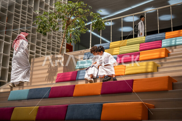 طالبان عربيان سعوديان خليجيان يجلسان على الأدراج في بهو المدرسه, المذاكره والمراجعه, الإستعداد للإمتحانات, بيئه مدرسيه تعليميه متطوره, التعليم الذكي, عالم جديد من التعليم، المدارس المبتكره, جودة التعليم, مدارس أكاديميه في المملكه العربيه السعوديه