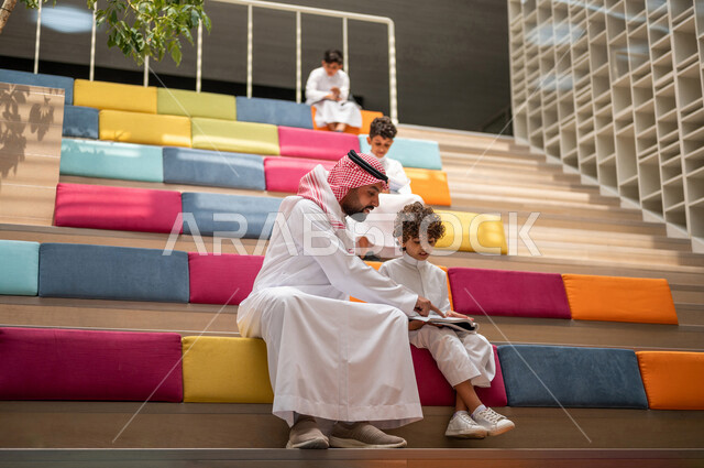 أستاذ عربي سعودي خليجي مع مجموعه من الطلاب يجلسون على الأدراج في بهو المدرسه, المذاكره والمراجعه, الإستعداد للإمتحانات, بيئه مدرسيه تعليميه متطوره, التعليم الذكي, عالم جديد من التعليم، المدارس المبتكره, جودة التعليم, مدارس أكاديميه في السعوديه
