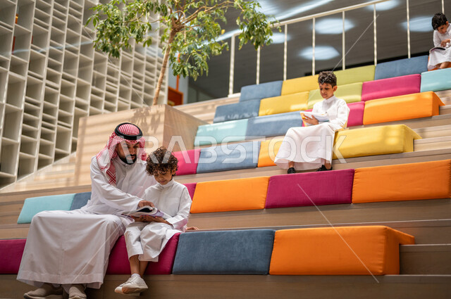 أستاذ عربي سعودي خليجي مع مجموعه من الطلاب يجلسون على الأدراج في بهو المدرسه, المذاكره والمراجعه, الإستعداد للإمتحانات, بيئه مدرسيه تعليميه متطوره, التعليم الذكي, عالم جديد من التعليم، المدارس المبتكره, جودة التعليم, مدارس أكاديميه في السعوديه