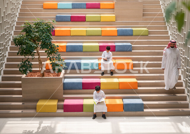 طالبان عربيان سعوديان خليجيان يجلسان على الأدراج في بهو المدرسه, المذاكره والمراجعه, الإستعداد للإمتحانات, بيئه مدرسيه تعليميه متطوره, التعليم الذكي, عالم جديد من التعليم، المدارس المبتكره, جودة التعليم, مدارس أكاديميه في المملكه العربيه السعوديه