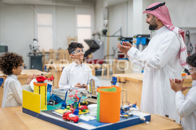 معلم عربي سعودي خليجي في بيئه مدرسيه تعليميه متطوره، متابعة مجموعة من الطلاب داخل الفصل, نظام التعليم المنتسوري, التعليم الذكي، عالم جديد من التعليم, تعزيز العلوم والإبتكارات, تنمية المهارات ، المدارس المبتكره, جودة التعليم, مدارس أكاديميه في السعوديه