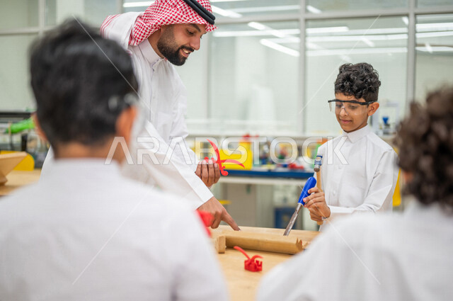 معلم عربي سعودي خليجي في بيئه مدرسيه تعليميه متطوره، متابعة مجموعة من الطلاب داخل الفصل, نظام التعليم المنتسوري, التعليم الذكي، عالم جديد من التعليم, تعزيز العلوم والإبتكارات, تنمية المهارات ، المدارس المبتكره, جودة التعليم, مدارس أكاديميه في السعوديه