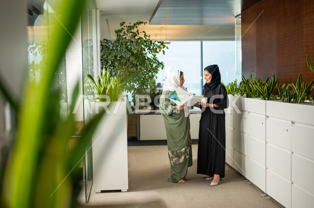 موظفتان عربيتان سعوديتان خليجيتان داخل مقر الشركة، ترتديان عبايات عصرية مميزة، أزياء محجبات، مهن و وظائف سعودية، شركة سعودية، سيدات أعمال، الحوارات والنقاشات، بيئة العمل، دردشة عمل، متابعة ومناقشة الأعمال