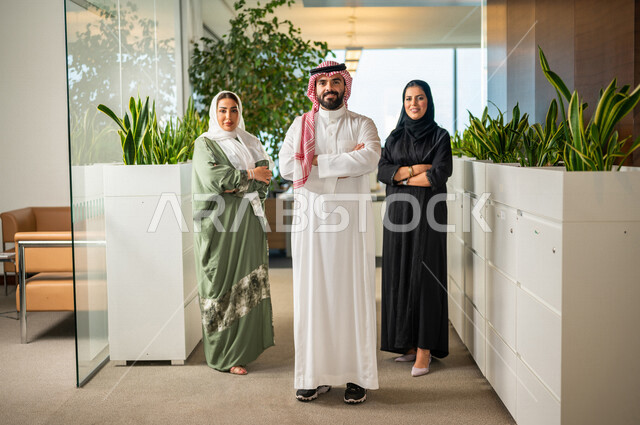 فريق عمل سعودي داخل مقر الشركة ، رجل وسيدات أعمال ينظرون إلى الكاميرا بإيدي متقاطعة ، مهن و وظائف سعودية ، شركة سعودية ، زملاء عمل، بيئة العمل ، تحقيق وتطوير الأهداف