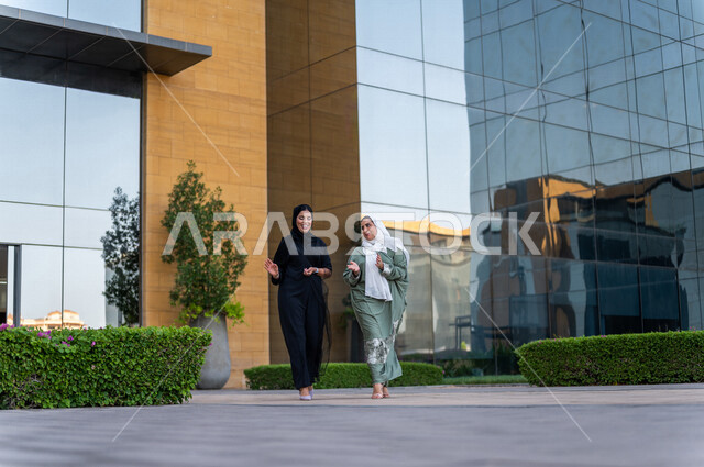 موظفتان عرببيتان سعوديتان خليجيتان خارج مبنى الشركة ، إنتهاء الساعات الرسمية للدوام ، خروج الموظفين ، مهن و وظائف سعودية ، مقر شركة سعودية ، سيدات أعمال ، الحوارات والنقاشات ، جولة خارج مبنى الشركة