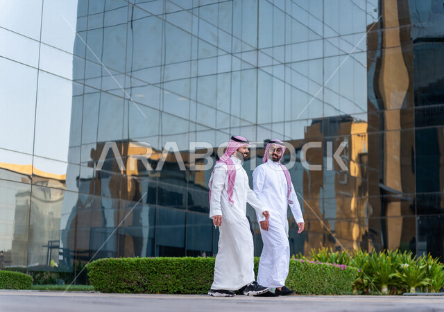 موظفان عربيان سعوديان خليجيان خارج مبنى الشركة ، إنتهاء الساعات الرسمية للدوام ، خروج الموظفين ، مهن و وظائف سعودية ، مقر شركة سعودية ، زملاء عمل ، الحوارات والنقاشات خارج مبنى الشركة ، متابعة ومناقشة الأعمال ، رجال أعمال