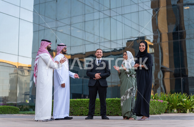 فريق عمل سعودي خارج مبنى الشركة ، حوار ومناقشة مع عميل يرتدي البدلة الرسمية ،  متابعة ومناقشة الأعمال ، مهن ووظائف سعودية ، مقر شركة سعودية ، زملاء عمل، الشراكة والتعاون